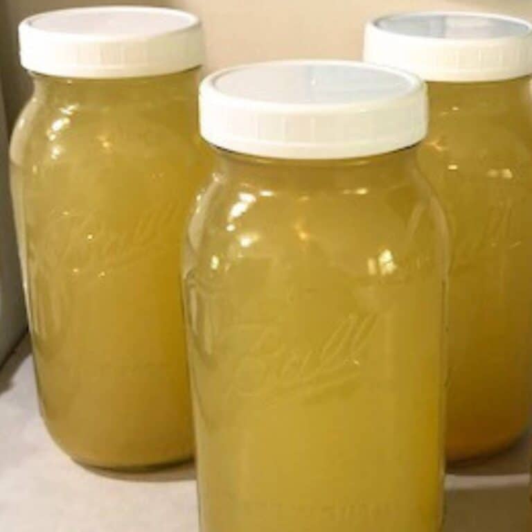 Glass mason jars of orange scrap vinegar on a kitchen counter.