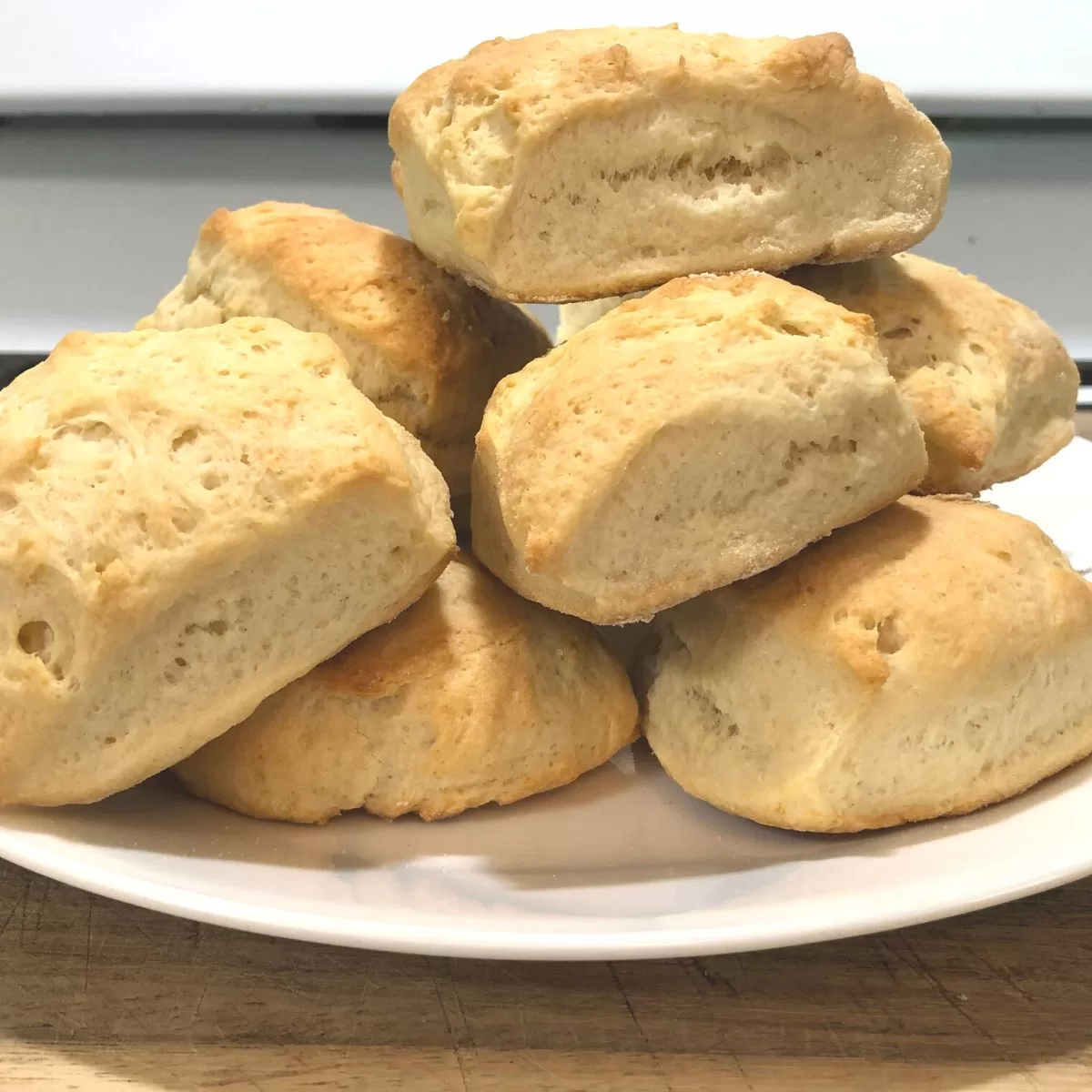 Homemade biscuits piled high on a white plate.