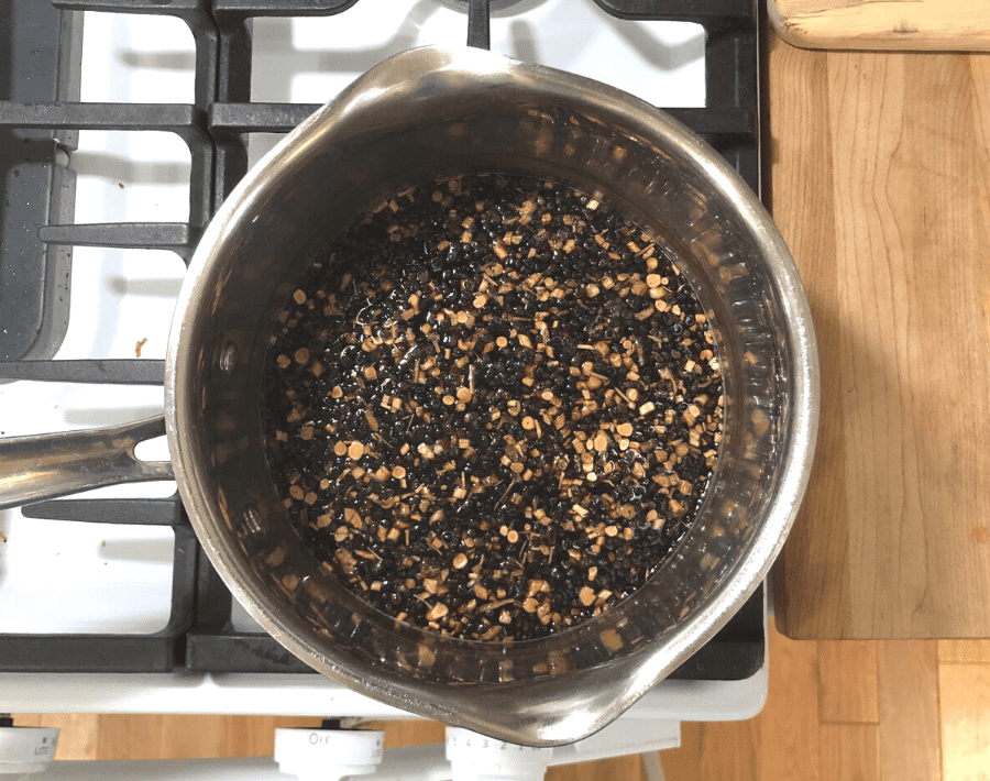 A pot on a stove with 4 cups of water, 1 cup dried elderberries, 1/2 cup dried astragalus root, and 1/4 cup dried echinacea root.