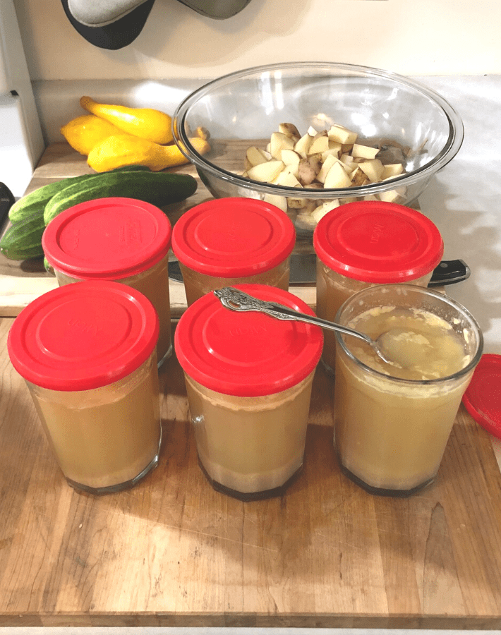 Vegetables on a wooden cutting board and jars of gelatinous chicken bone broth.
