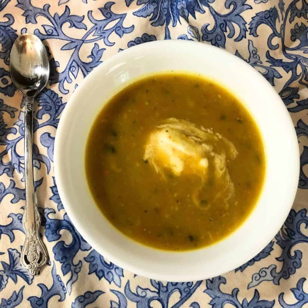 Bowl of creamy vegetable soup on a blue and white paisley napkin.