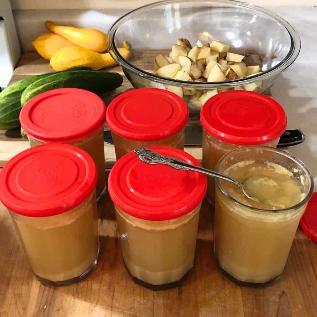 Vegetables on a wooden cutting board and jars of gelatinous chicken bone broth.