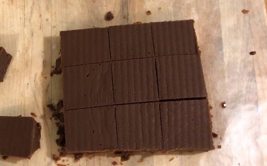 Six pieces of chocolate fudge on wax paper.