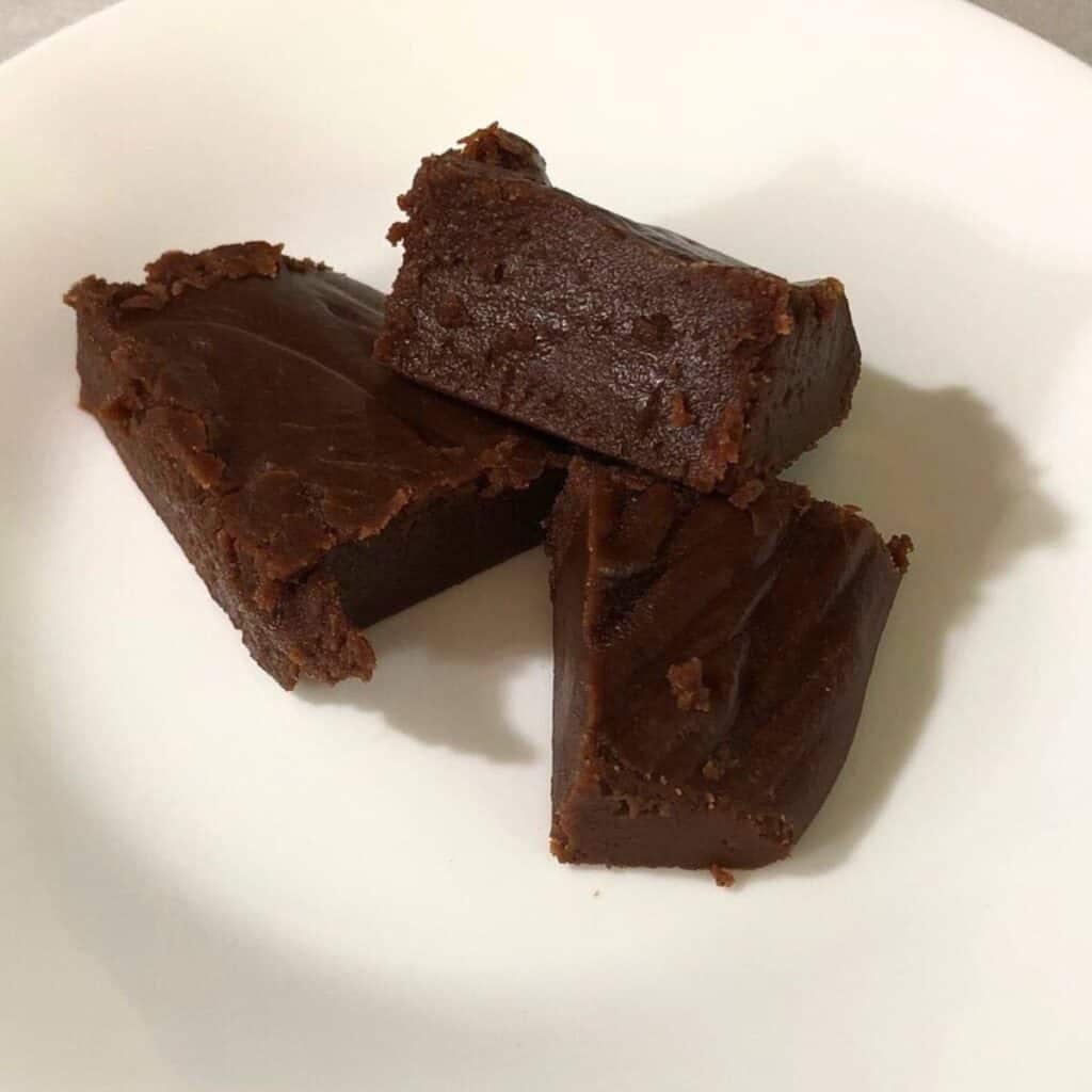 Three pieces of chocolate fudge on a white plate.