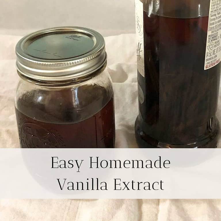 A glass pint jar and liter bottle filled with homemade vanilla extract, sitting on a white flour sack towel on the counter.