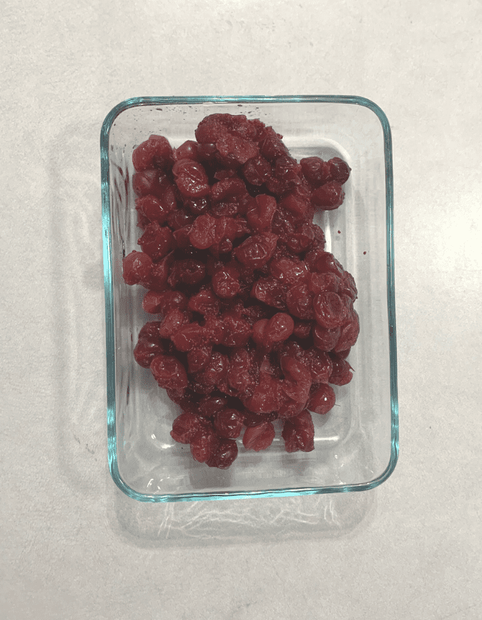 A glass dish of apple juice-infused cranberries sitting on a counter.