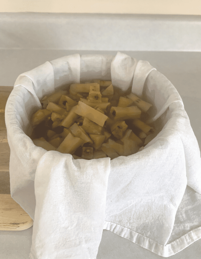 Apple scraps and apple juice poured into a bowl lined with a white flour sack towel.