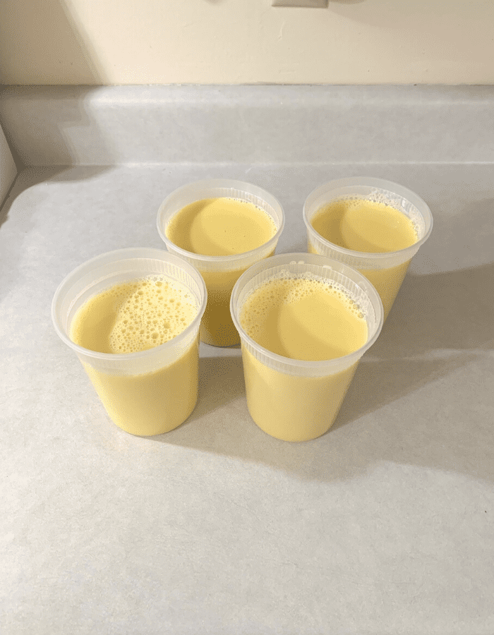 Four quarts of bright yellow to orange cow colostrum sitting on a counter.