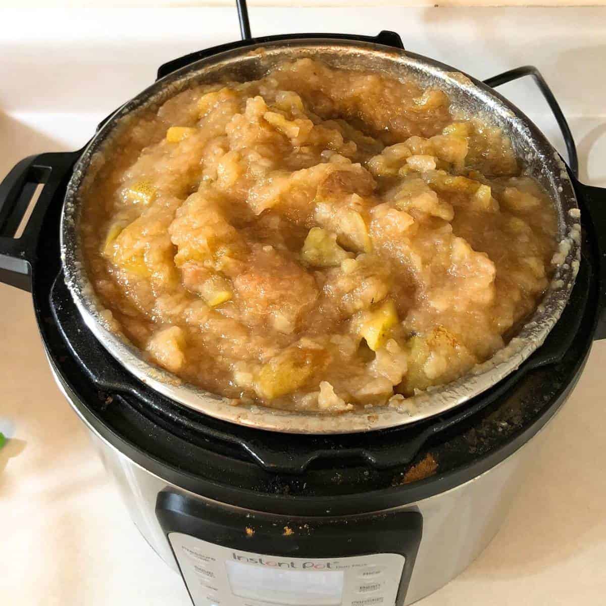 An instant pot with soft apple butter cooking inside.