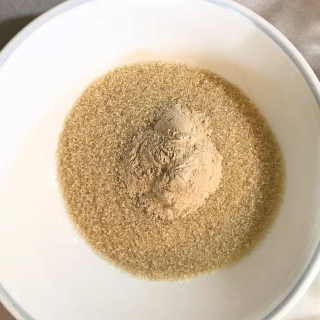 A white bowl with cane sugar and Pomona's pectin in it.