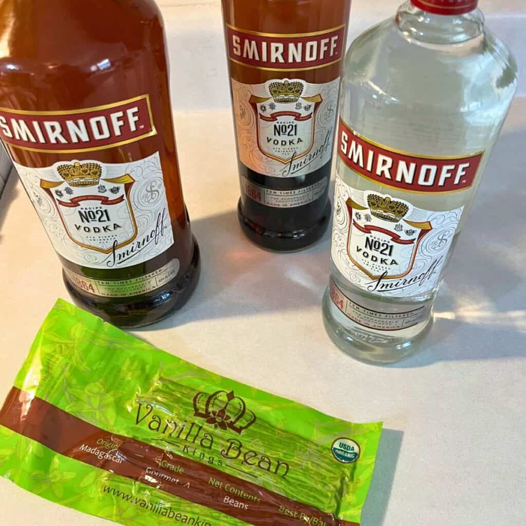 Bottles of homemade vanilla extract sitting on a counter next to a bottle of vodka and a package of grade A Madagascar vanilla beans.