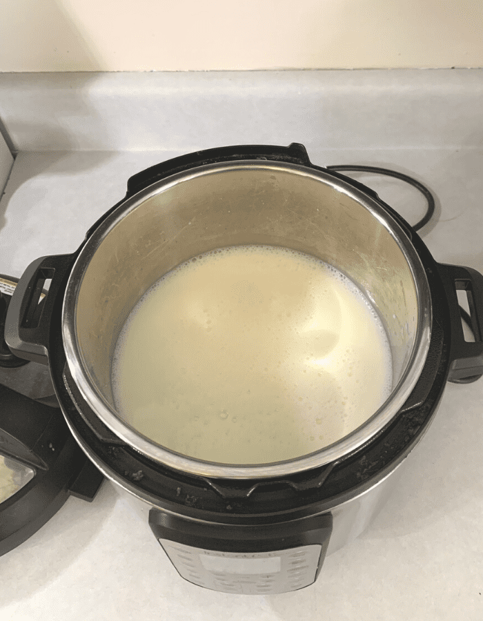 An Instant Pot sitting on a kitchen counter with raw milk inside.