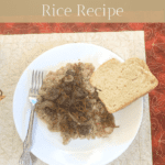 Sausage and liver rice on a white plate next to a slice of bread. A silver fork is on the plate and the plate is sitting on a fall-themed quilted placemat.