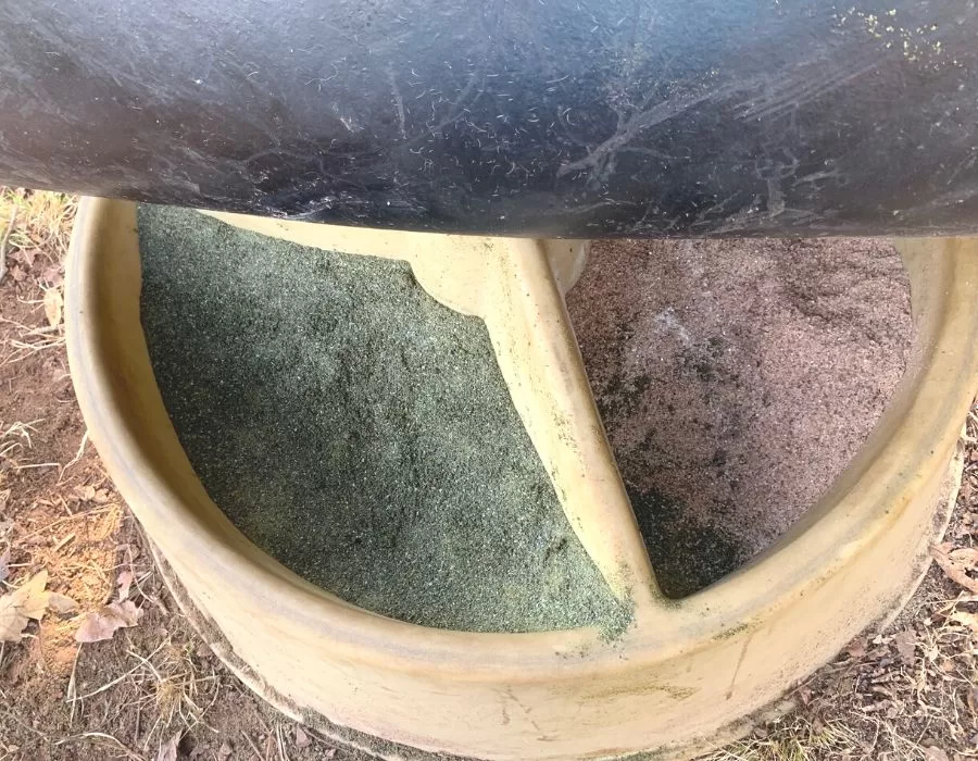 A round cow mineral feeder with the lid open to show green sea kelp and red sea salt.