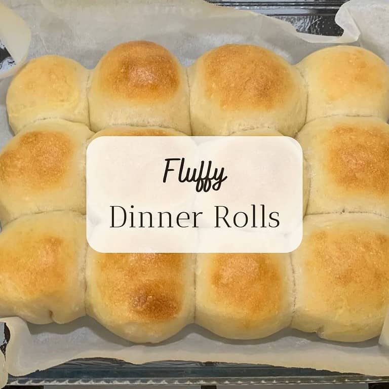 A dozen dinner rolls in a glass pan on top of a stove. The title is "Fluffy Dinner Rolls."