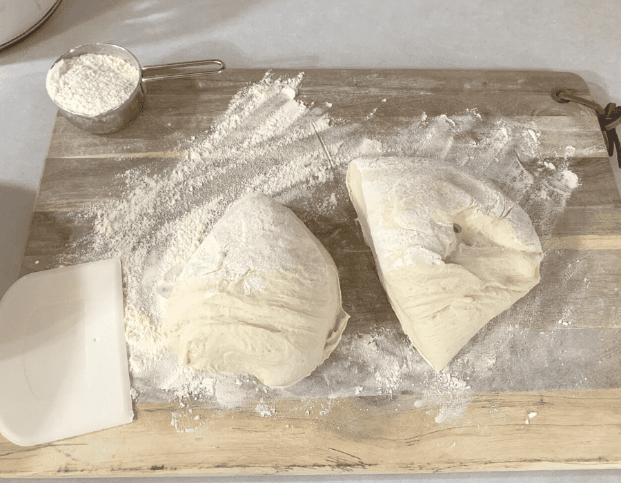 Dinner roll bread dough on a floured wood cutting board.