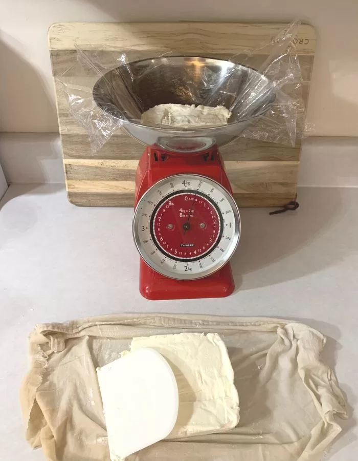 A mechanical kitchen scale weighing cream cheese.