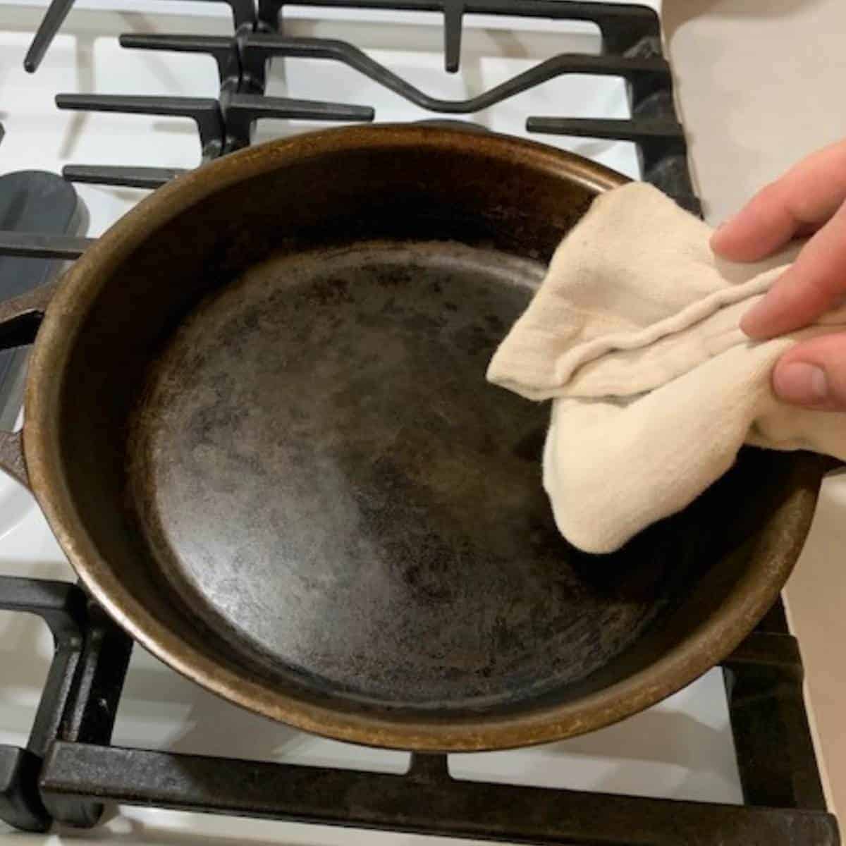 Woman wiping out a cast iron skillet.