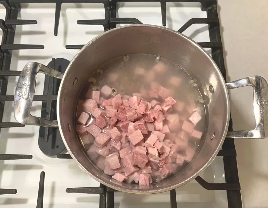 Black eyed peas and ham chunks in a large pot on the stove with chicken bone broth.