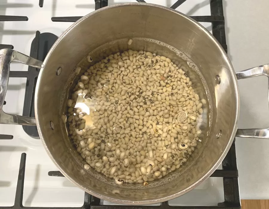 Black eyed peas and chicken bone broth in a large pot on the stove.