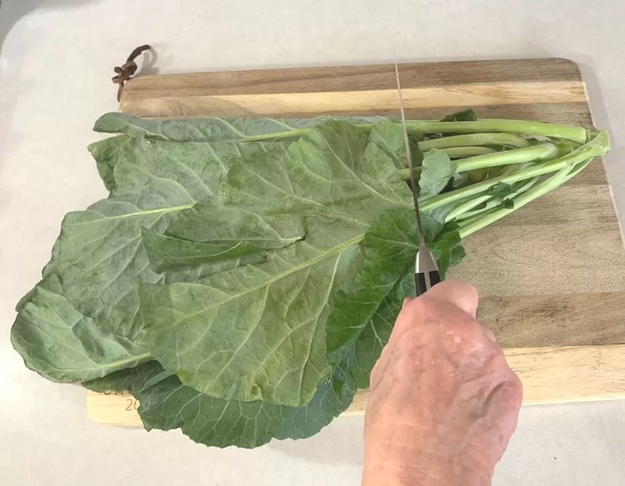 Woman cutting stems off collard greens. Southern Black Eyed Peas and Collard Greens.