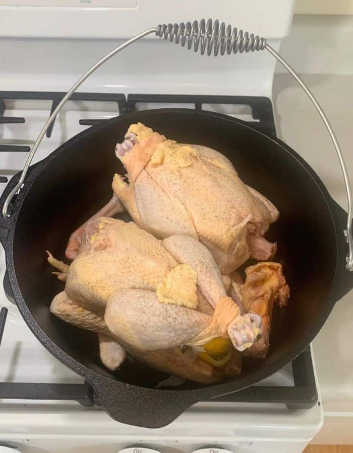 Whole chickens stuffed with garlic and lemon inside a cast iron Dutch oven.