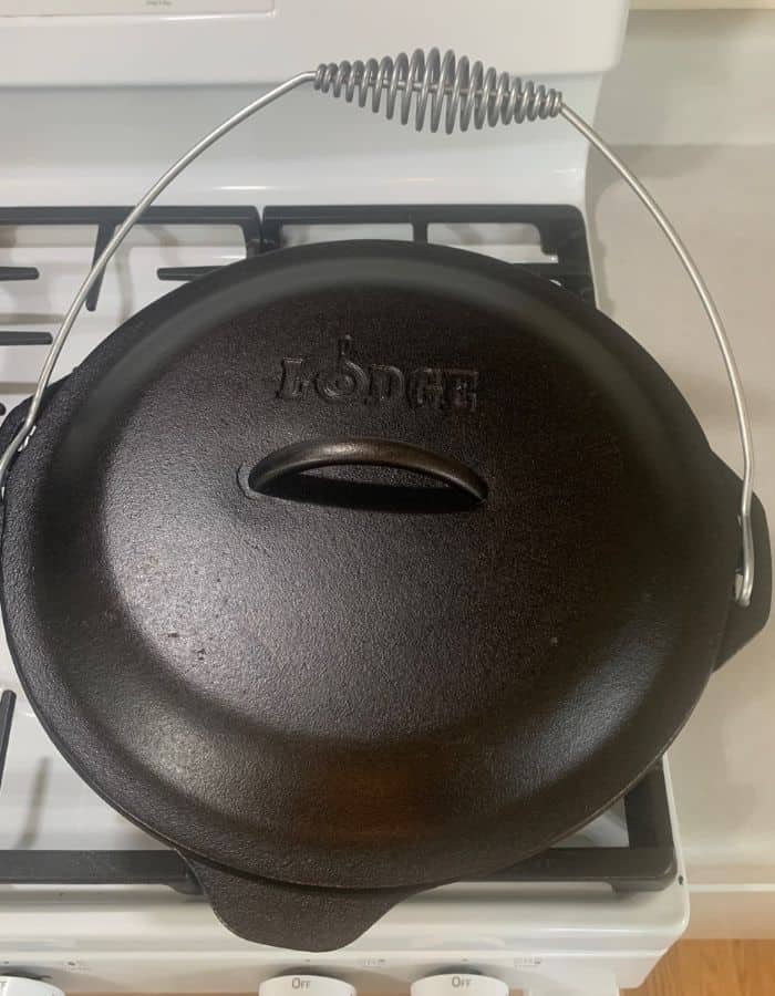 A Lodge cast iron Dutch oven with the lid on sitting on a stove.