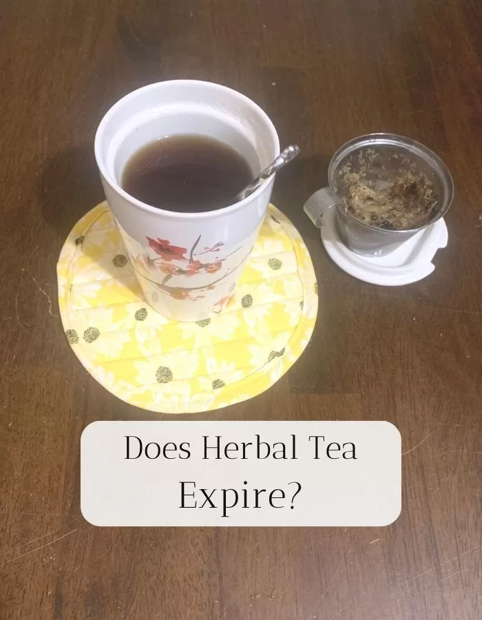 Herbal tea in a tea cup on a yellow coaster. The title is "Does Herbal Tea Expire"?
