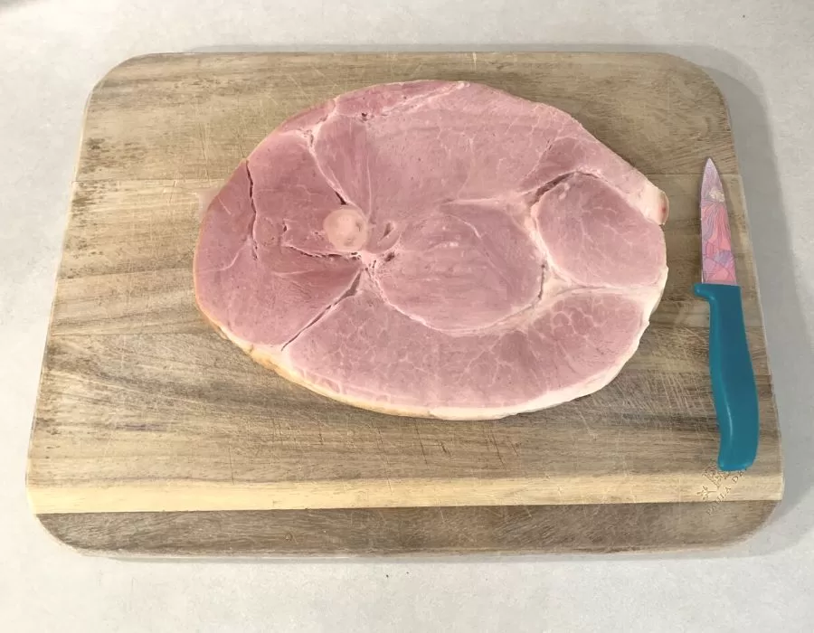 A ham steak on a wood cutting board.