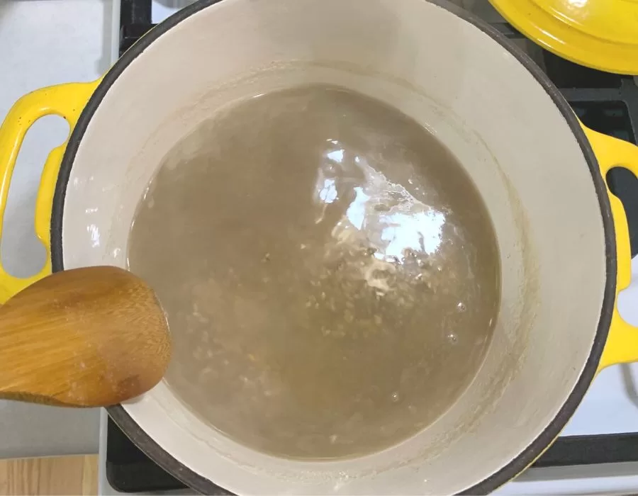 Rice and chicken bone broth in a yellow dutch oven on the stove.