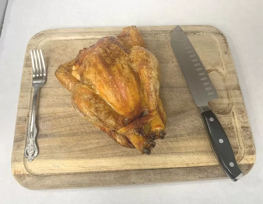 Cooked whole chicken on a wood cutting board.