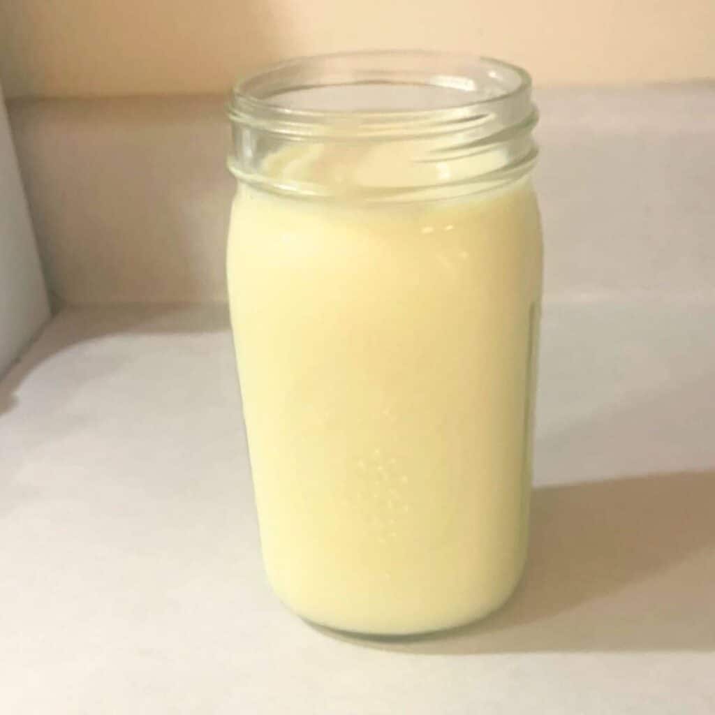 A quart mason jar of cow milk sitting out on a kitchen counter.