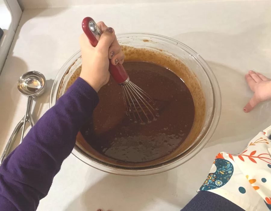 Little girls whisking ingredients to make chocolate cupcakes.