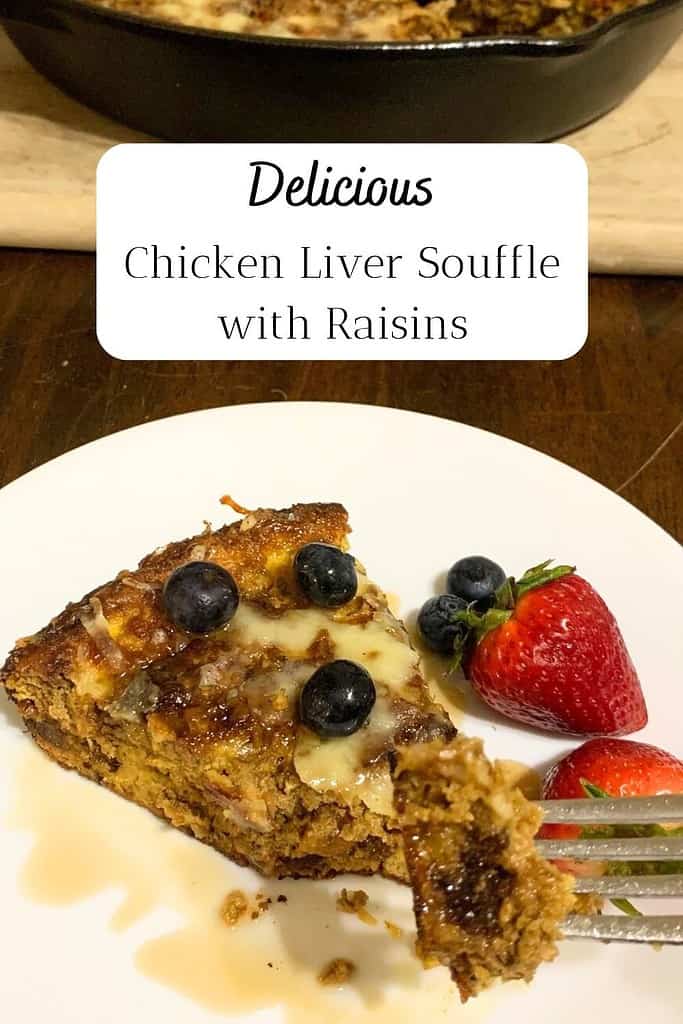 A slice of chicken liver souffle with blueberries and strawberries on a white plate on a dark kitchen table. The title is "Delicious Chicken Liver Souffle with Raisins."