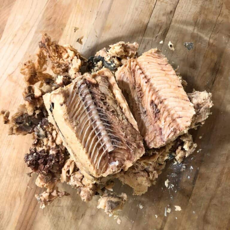 A large, glass bowl with canned salmon opened to show the bones and skin.