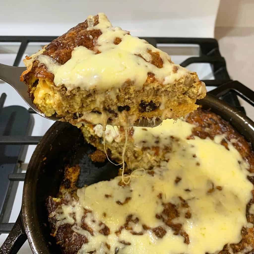 Woman holding a spatula of chicken liver souffle from a cast iron skillet.