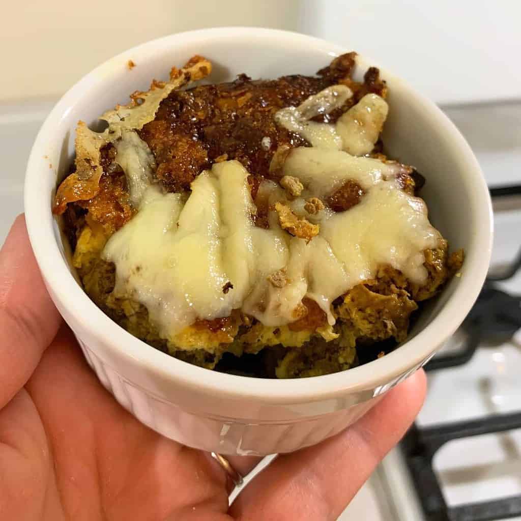 Woman holding chicken liver souffle in a white ramekin.