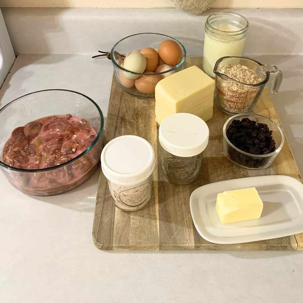 Ingredients for making chicken liver souffle with raisins on the kitchen counter including chicken livers, salt, pepper, butter, raisins, milk, cheddar cheese, raisins, oats, milk, and eggs.