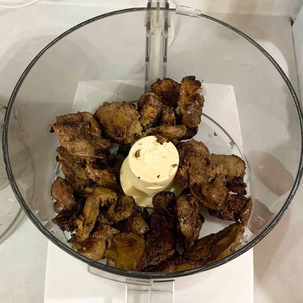 Cooked chicken livers in a food processor on the counter.