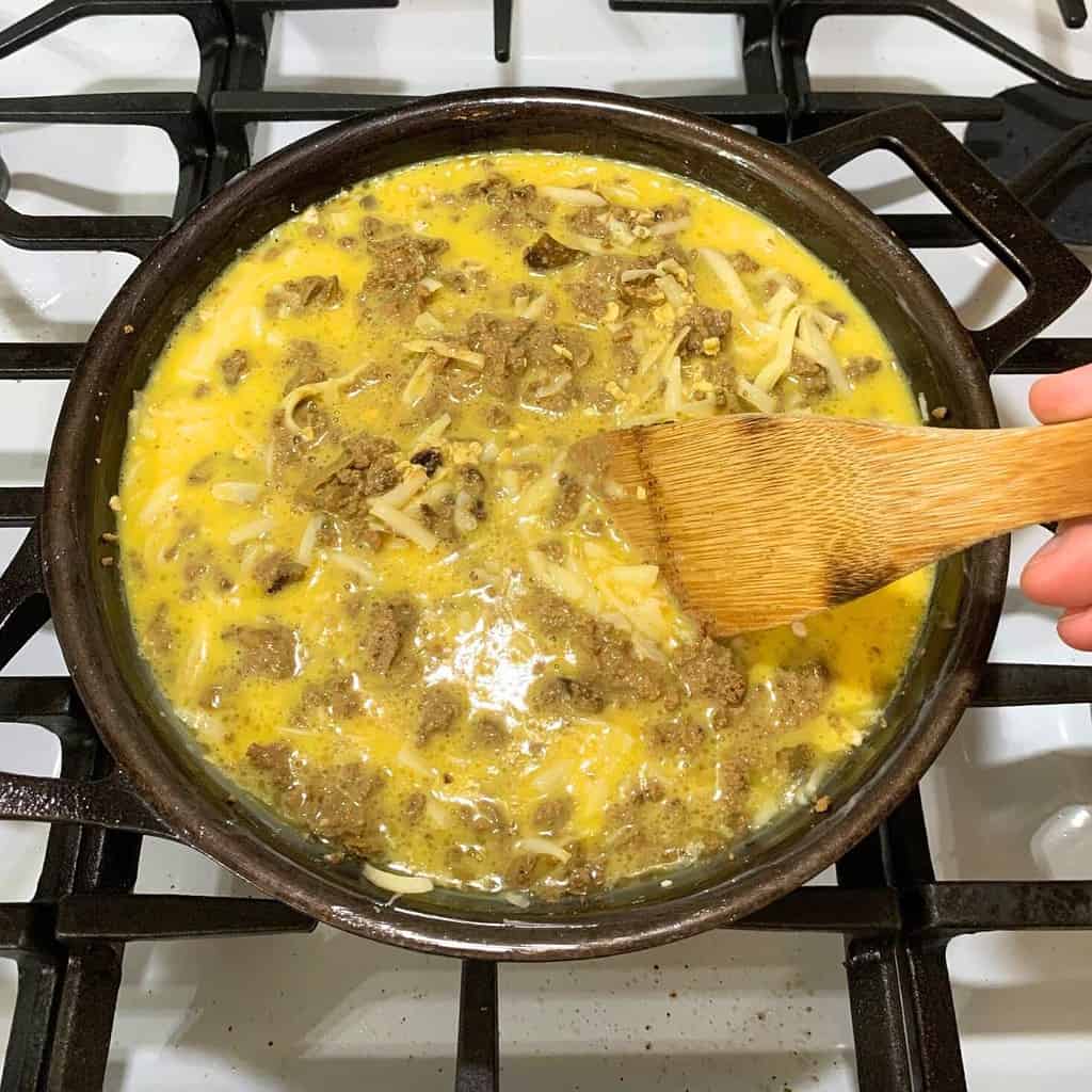 Uncooked chicken liver souffle ingredients in a cast iron skillet on top of a stove.