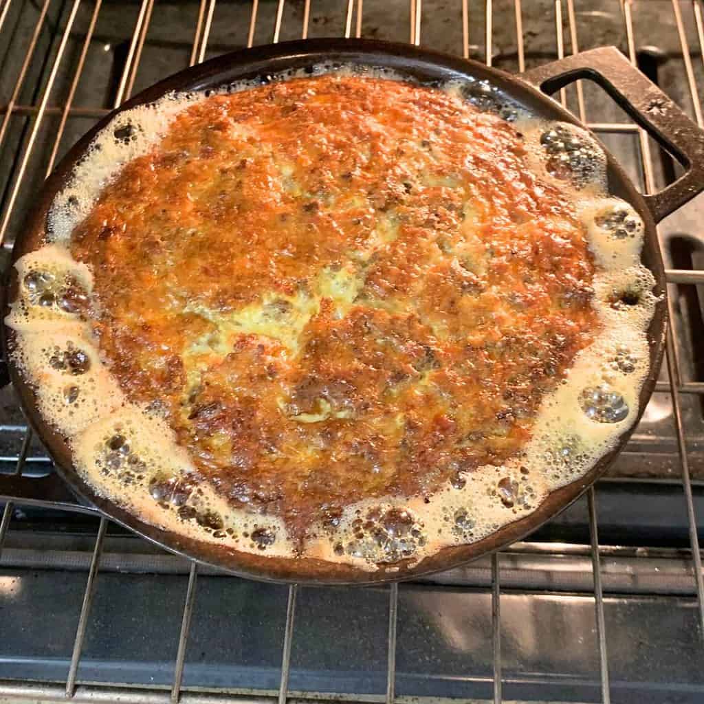 Hot chicken liver souffle in a cast iron skillet in the oven.