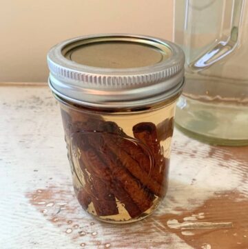 Cinnamon sticks inside a half-pint mason jar filled with vodka and topped with a lid.