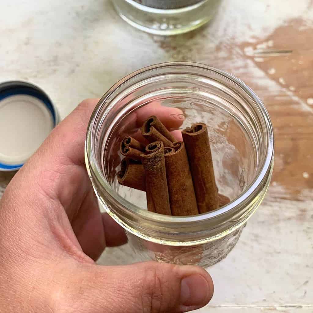 Cassia vs ceylon cinnamon.  Woman holding a glass mason jar with cinnamon sticks inside.