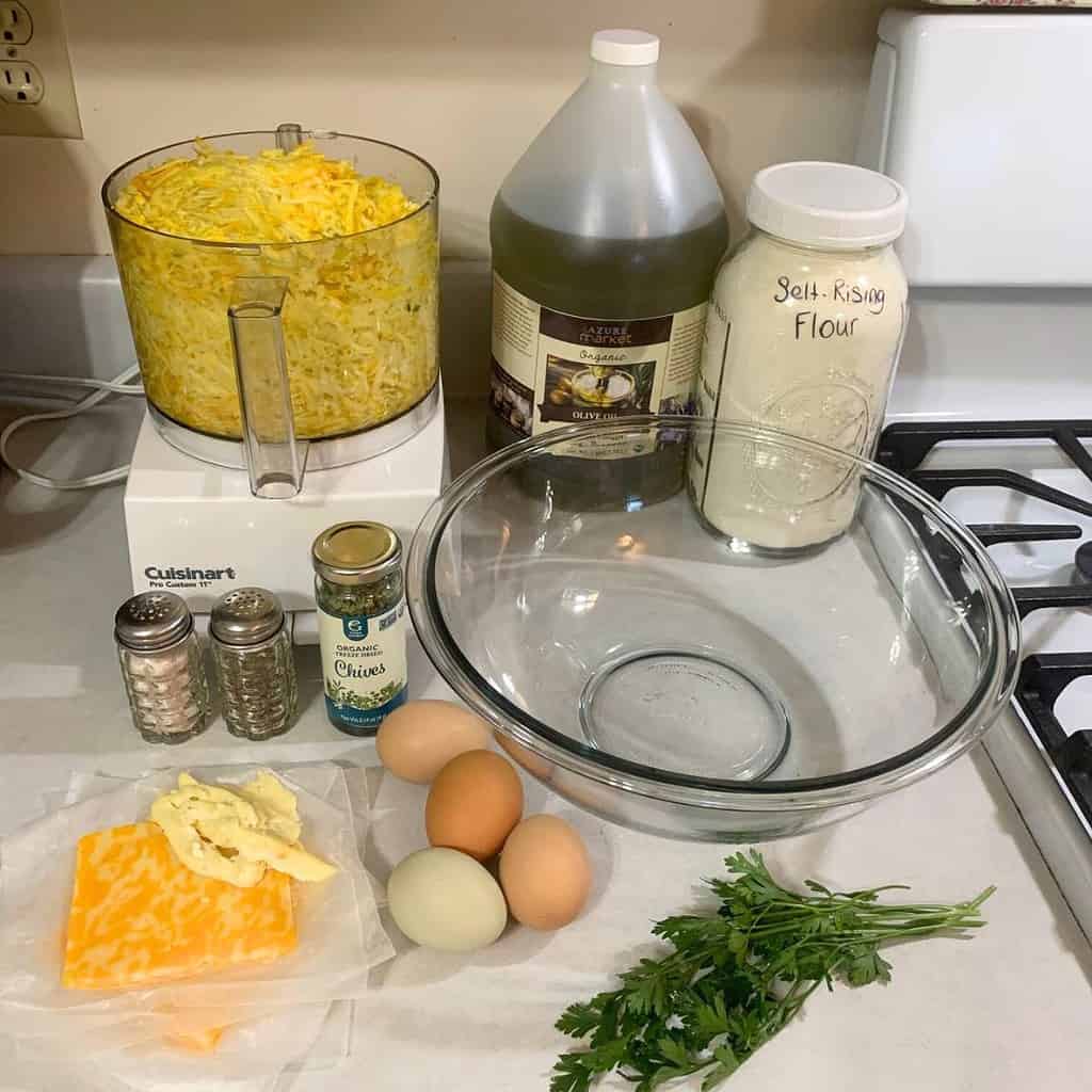 Ingredients for making cheesy zucchini casserole including grated zucchini, eggs, cheese, oil, self-rising flour, and herbs and spices.