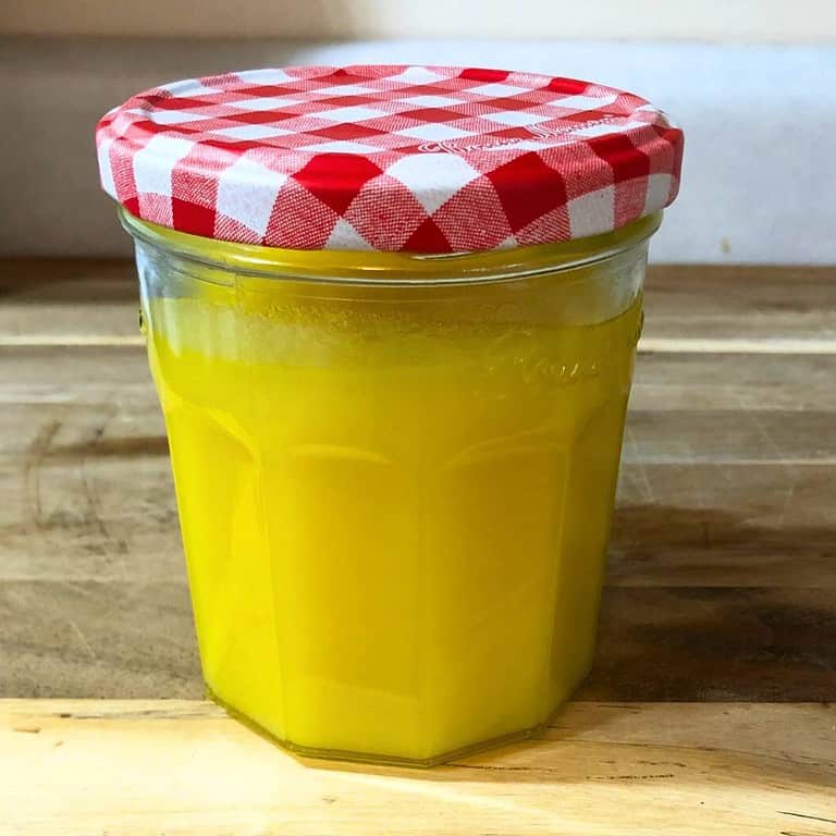 Rendered chicken fat schmaltz in a glass jar with a red and white lid.