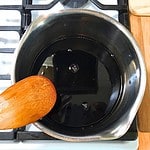 Dark purple elderberry syrup in a medium stainless steel pot on the stove.