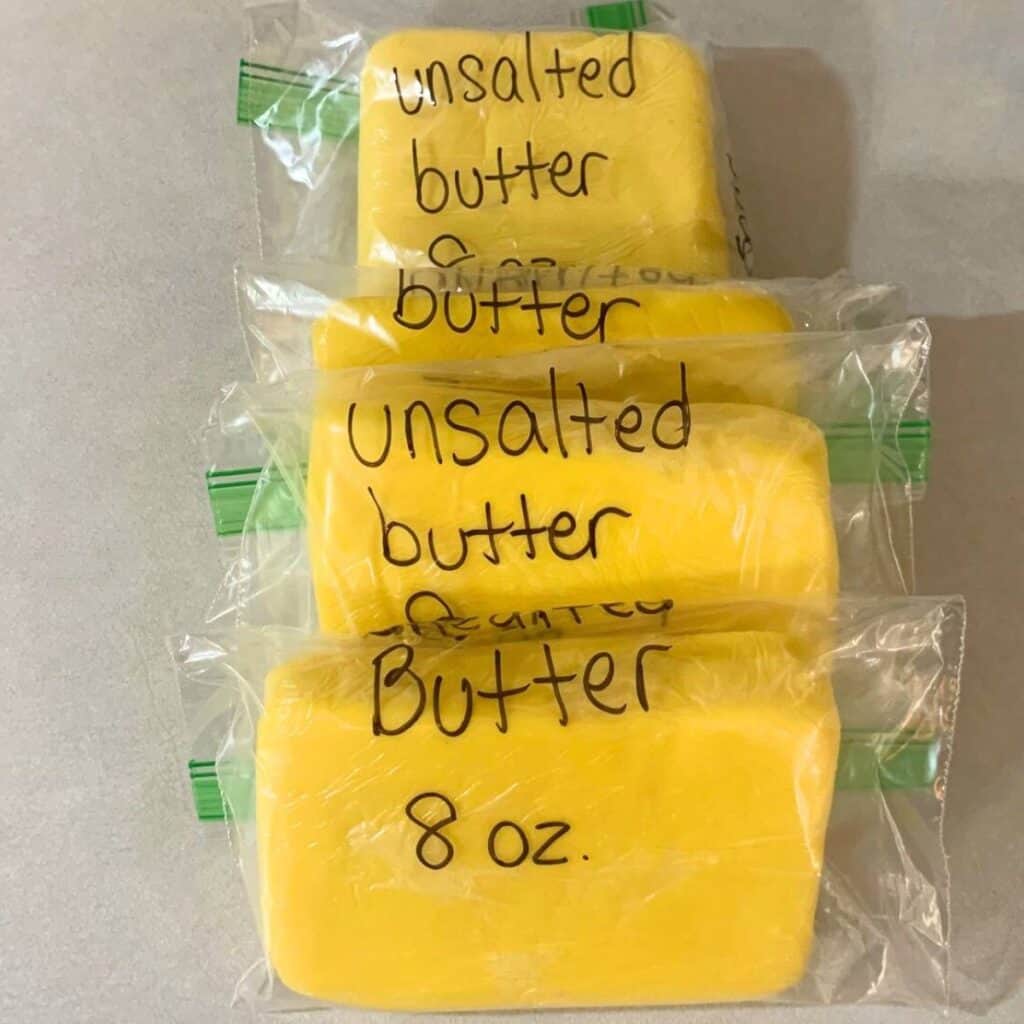 Four packages of homemade butter in freezer bags labeled "unsalted butter, eight ounces."