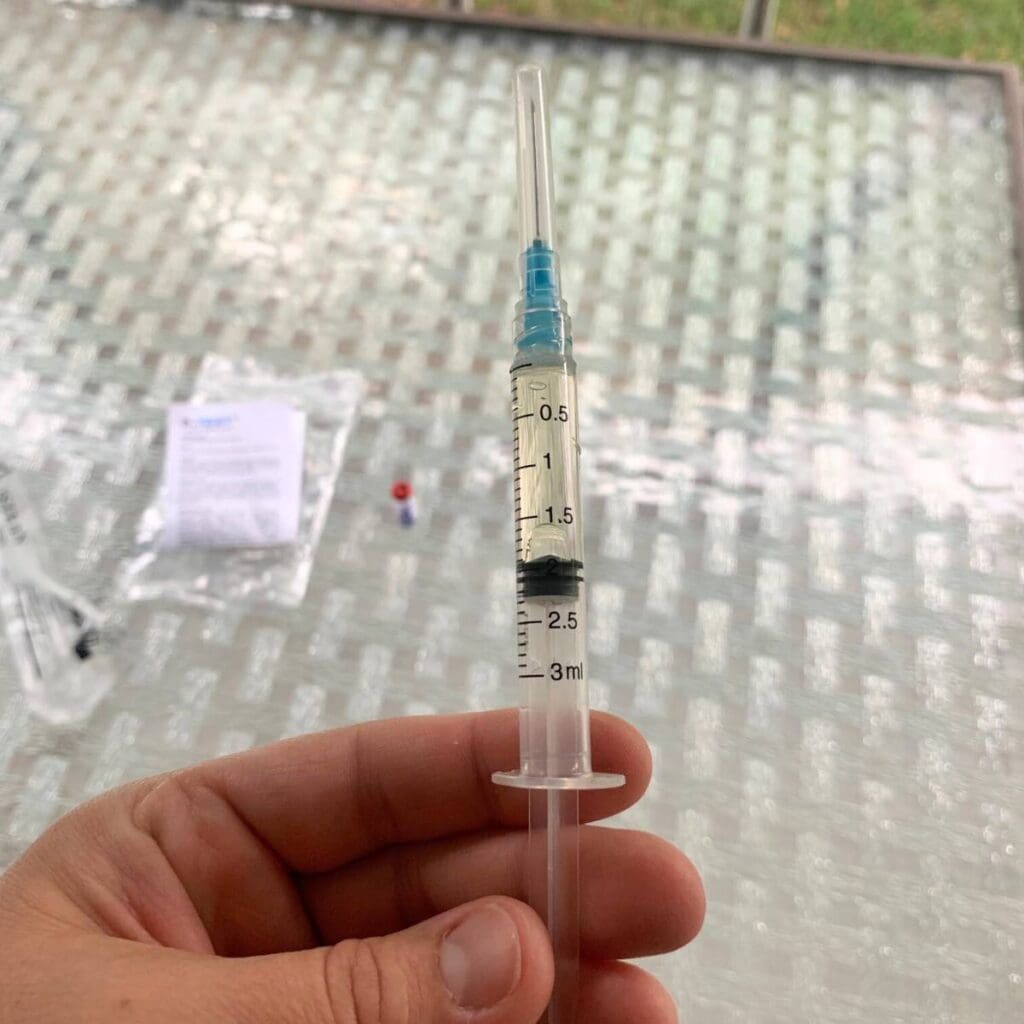 Woman holding a plastic syringe filled with cow urine.