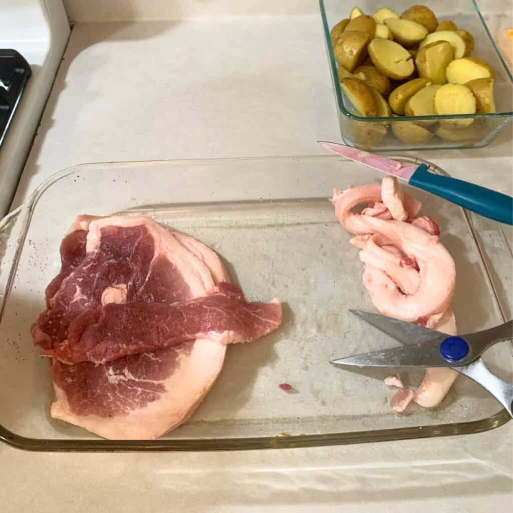 Fresh ham steaks in a glass dish with the fat cut off and pushed to the side.