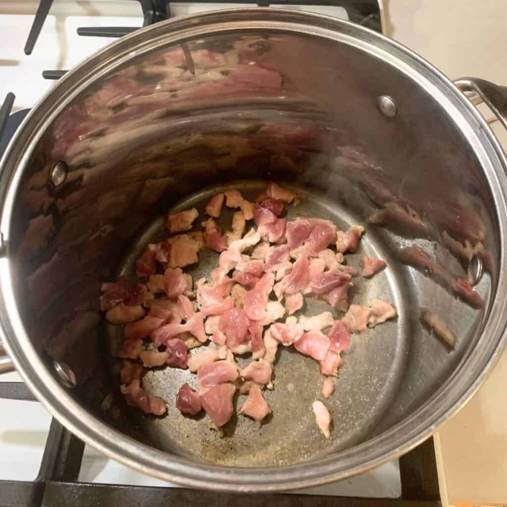 Cubed ham cooking in a large stainless steel pot.